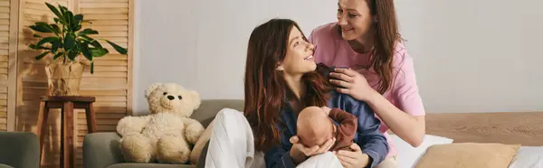 Two loving mothers share a tender moment with their child, creating a cozy family atmosphere. — Stock Photo