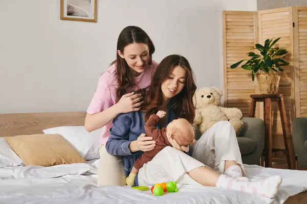Two loving mothers enjoy a joyful Mothers Day, creating cozy moments with their child at home. — Stock Photo