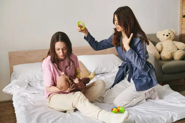 Two loving mothers share a tender moment with their baby in a warm, inviting bedroom. — Stock Photo