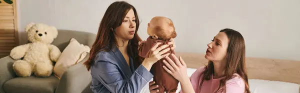 Two mothers share a tender moment with their child in a warm and inviting home setting. — Stock Photo