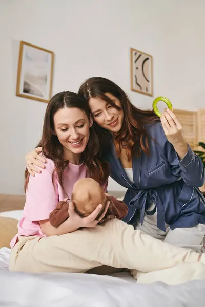 Zwei liebevolle Mütter umarmen ihr Kind am Muttertag und erfüllen ihr Zuhause mit Freude. — Stockfoto