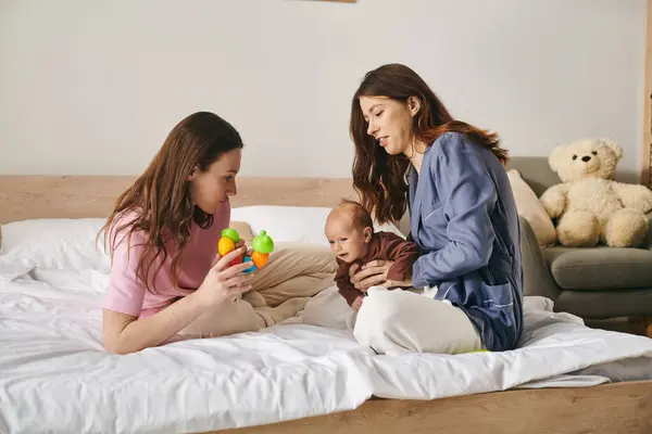 Two devoted mothers celebrate Mothers Day at home, happily playing with their child. — Stock Photo