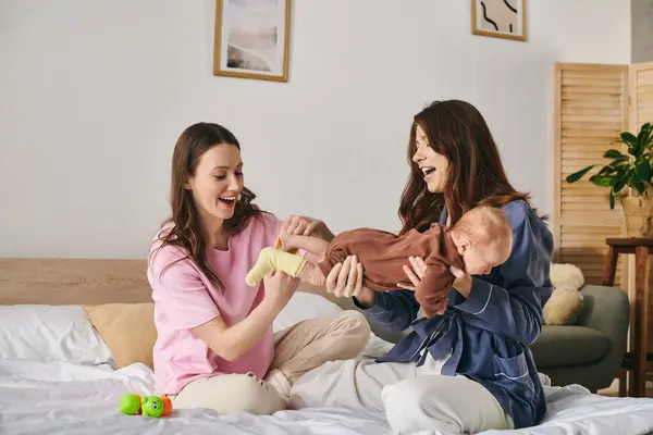 Two mothers share a cozy moment with their baby, celebrating the warmth of family on Mothers Day. — Stock Photo