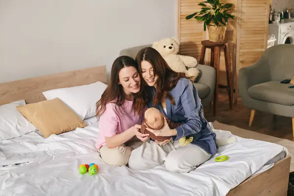 Dos madres cariñosas disfrutan de un momento tierno con su bebé en un ambiente cálido y acogedor. — Stock Photo