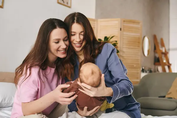 Two joyful mothers share a tender moment with their child in a warm, comfortable setting. — Stock Photo