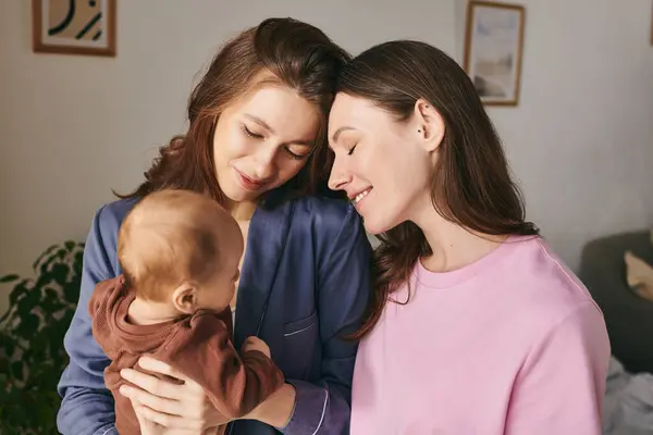 Two mothers joyfully embrace their child in their warm, inviting home, celebrating love and family. — Stock Photo