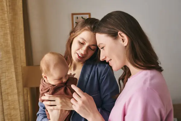 Two loving mothers share a joyful moment with their baby, embracing motherhood on this special day. — Stock Photo