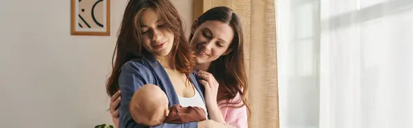 Two joyful mothers embrace their baby at home, cherishing a special Mothers Day moment together. — Stock Photo