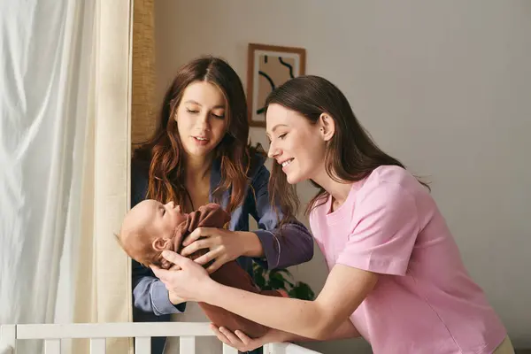 Two mothers share a tender moment while joyfully caring for their baby in a warm home setting. — Stock Photo
