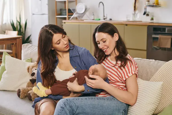 Two loving mothers celebrate Mothers Day at home, nurturing their child in a warm, inviting space. — Stock Photo