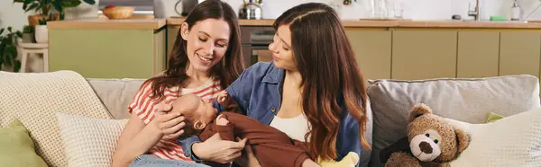 Two joyful mothers share a tender moment with their baby while celebrating Mothers Day at home. — Stock Photo