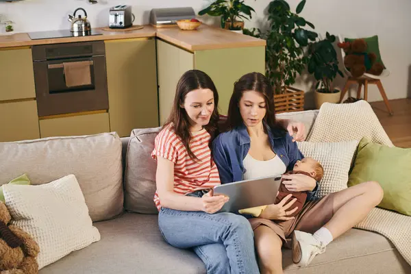 Two mothers share a loving moment at home with their child, enjoying quality time together. — Stock Photo