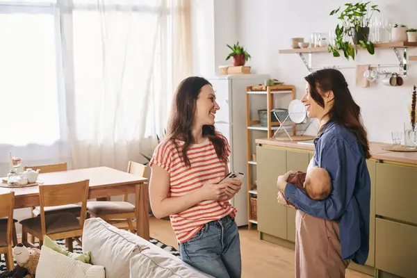 Two joyful mothers share a tender moment in their cozy home while celebrating mothers day together. — Stock Photo