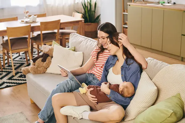 Two loving mothers cherish their baby together in a warm home on Mothers Day. — Stock Photo