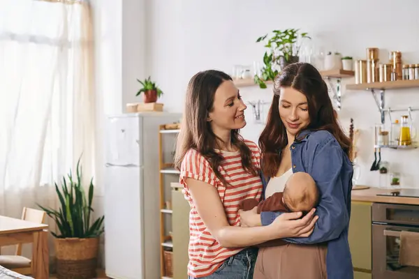 In a cozy kitchen, two mothers joyfully celebrate Mothers Day with their lovely baby. — Stock Photo