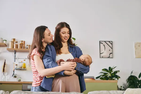 Two loving mothers embrace their newborn child in a warm, inviting home on Mothers Day. — Stock Photo