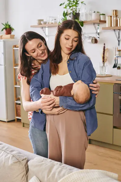 Two loving mothers cherish a joyful Mothers Day moment with their baby in a warm home setting. — Stock Photo