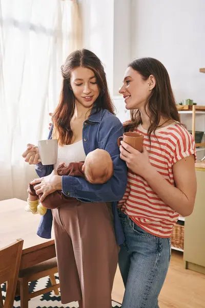 Zwei Mütter verbringen einen warmen Moment und feiern den Muttertag mit ihrem Kind in gemütlicher Atmosphäre zu Hause. — Stockfoto
