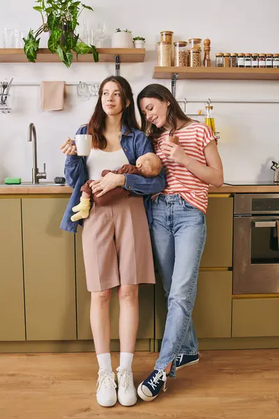 Two loving mothers enjoy a cozy moment in their home, celebrating Mothers Day with their child. — Stock Photo