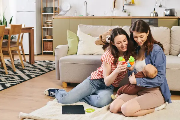 Two loving mothers share special moments with their baby, celebrating family at home. — Stock Photo