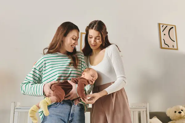 Two loving mothers share a joyful moment with their baby in a warm, inviting home setting. — Stock Photo