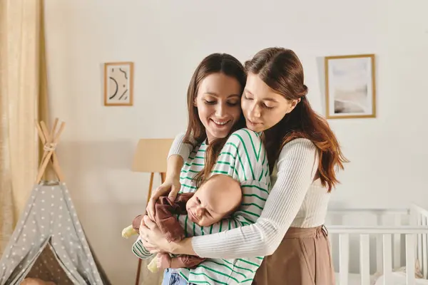 Dos madres alegres aprecian un momento tierno con su bebé en el Día de las Madres. - foto de stock