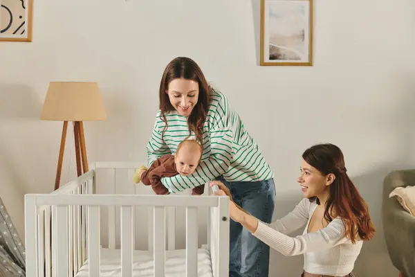 Two mothers joyfully care for their baby in a warm and inviting living room setting. — Stock Photo