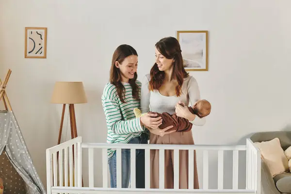 Two loving mothers joyfully bond with their baby in a cozy home setting celebrating Mothers Day. — Stock Photo