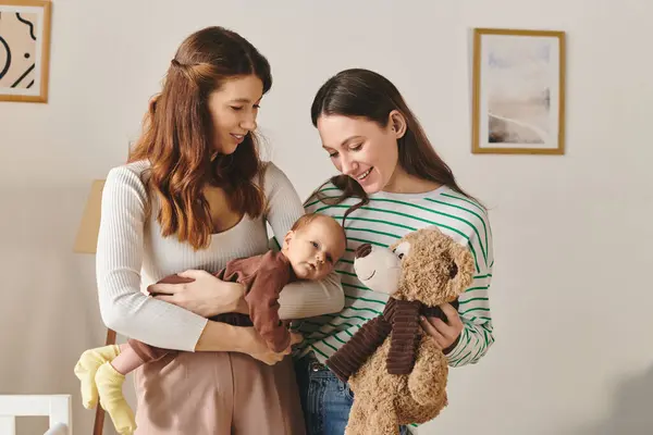 Two mothers share a tender moment with their baby, creating memories on Mothers Day at home. — Stock Photo