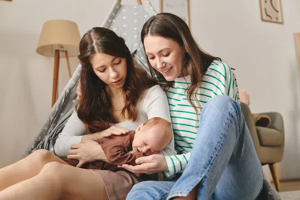 Two loving mothers enjoy a tender moment with their baby in a warm and inviting home setting. — Stock Photo