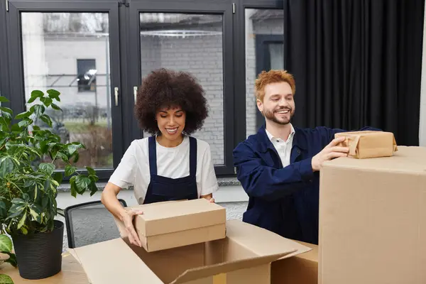 Two friends joyfully unpack their belongings together while preparing their new living space. — Stock Photo