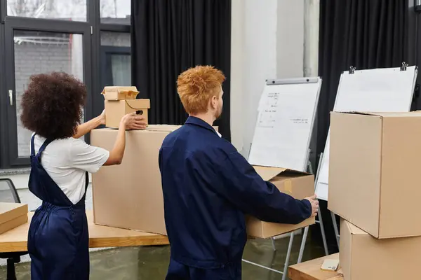 Zwei Personen packen in einem modernen Arbeitsraum Kisten ein und aus und demonstrieren Teamwork. — Stockfoto