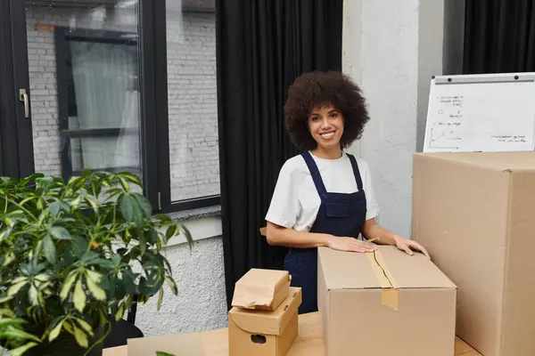 A young woman smiles while packing boxes in her stylish apartment. — Stock Photo