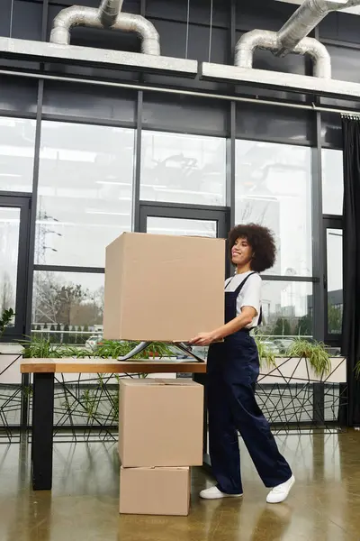 A woman lifts a large cardboard box in a contemporary setting, embodying the spirit of moving. — Stock Photo