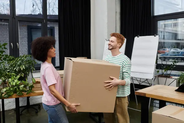 Zwei Menschen packen freudig Kartons in einem hellen Raum voller Pflanzen und Umzugsmaterial ein und aus — Stockfoto