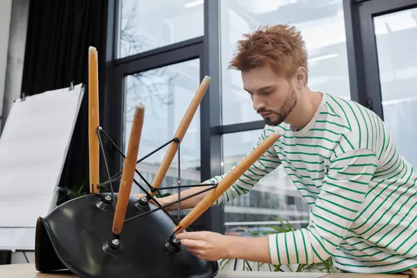 A young man carefully disassembles office furniture as preparations for relocation begin. — Stock Photo