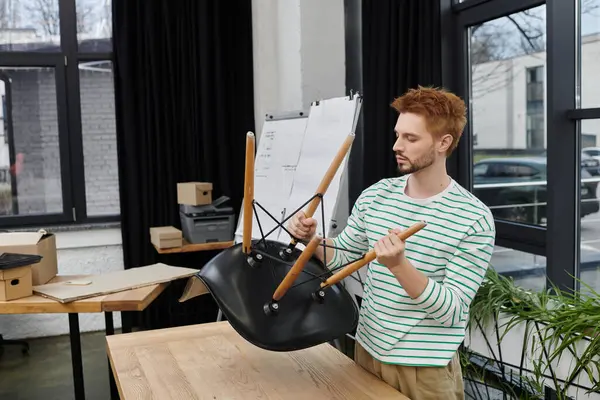 Un hombre expertamente monta una silla en una oficina moderna mientras se prepara para reubicarse. - foto de stock