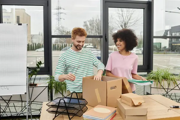 Two cheerful individuals unpacking boxes and organizing supplies in a bright modern workspace — Stock Photo