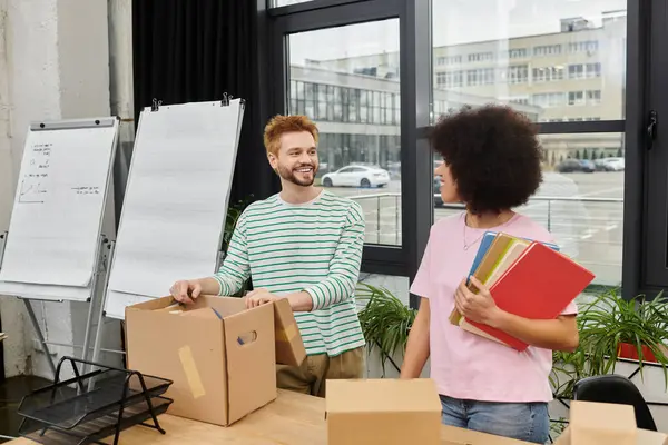 Zwei Menschen genießen einen unbeschwerten Moment beim Packen und Auspacken von Kartons im Büro. — Stockfoto