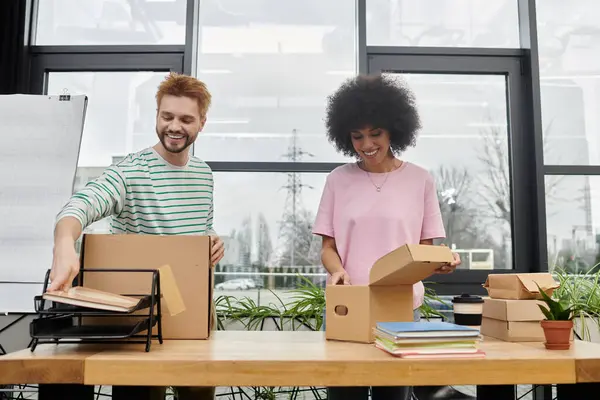 Zwei Menschen sind damit beschäftigt, in einem hellen, grünen, modernen Raum zu packen und auszupacken.. — Stockfoto
