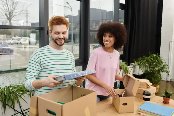 A happy couple organizes boxes together in a modern office space. — Stock Photo