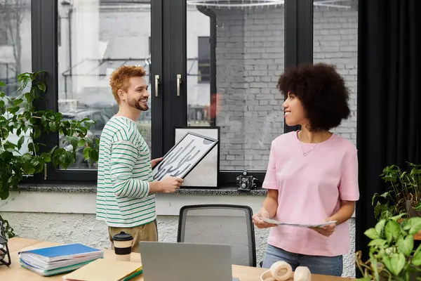 Two individuals actively sort and arrange items in a bright, contemporary office setting. — Stock Photo