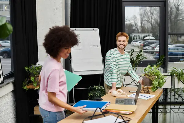 Due colleghi collaborano in uno spazio di lavoro moderno mentre selezionano e organizzano i loro effetti personali. — Foto stock
