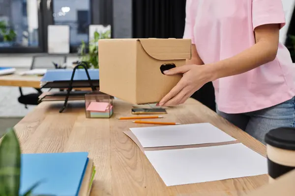 A woman packs a box in a bright, modern office, preparing for a move. — Stock Photo