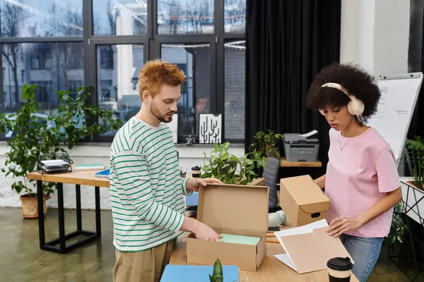 Two people pack and unpack in a modern office filled with plants. — Stock Photo