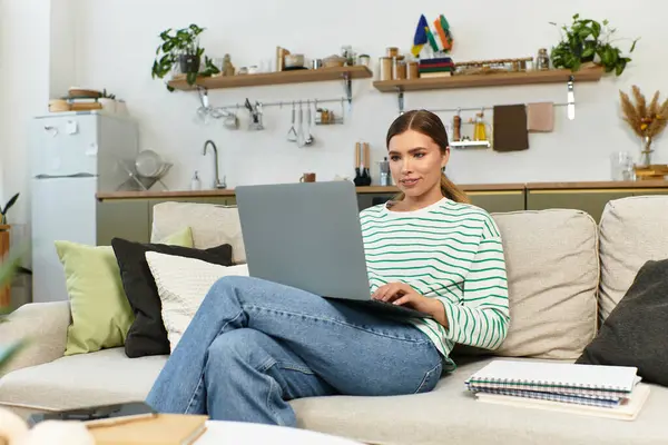 A young woman smiles at her laptop in a stylish, plant filled living space. — Stock Photo