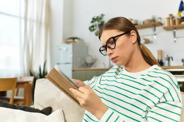 A young woman is happily reading in a bright, modern living space. — Stock Photo