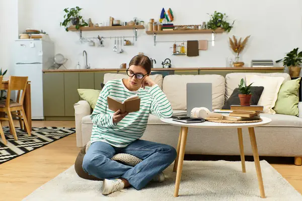 A stylish young woman lounges on a rug, engrossed in her book amid vibrant decor. — Stock Photo