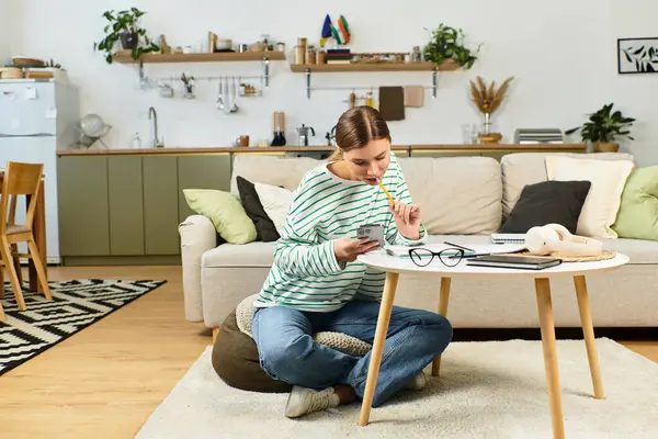 A young woman sits on the floor, amused by her phone in a stylish living space. — Stock Photo