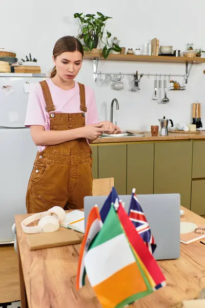 Hermosa mujer joven de pie en una cocina elegante, se centró en su computadora portátil mientras trabajaba. - foto de stock